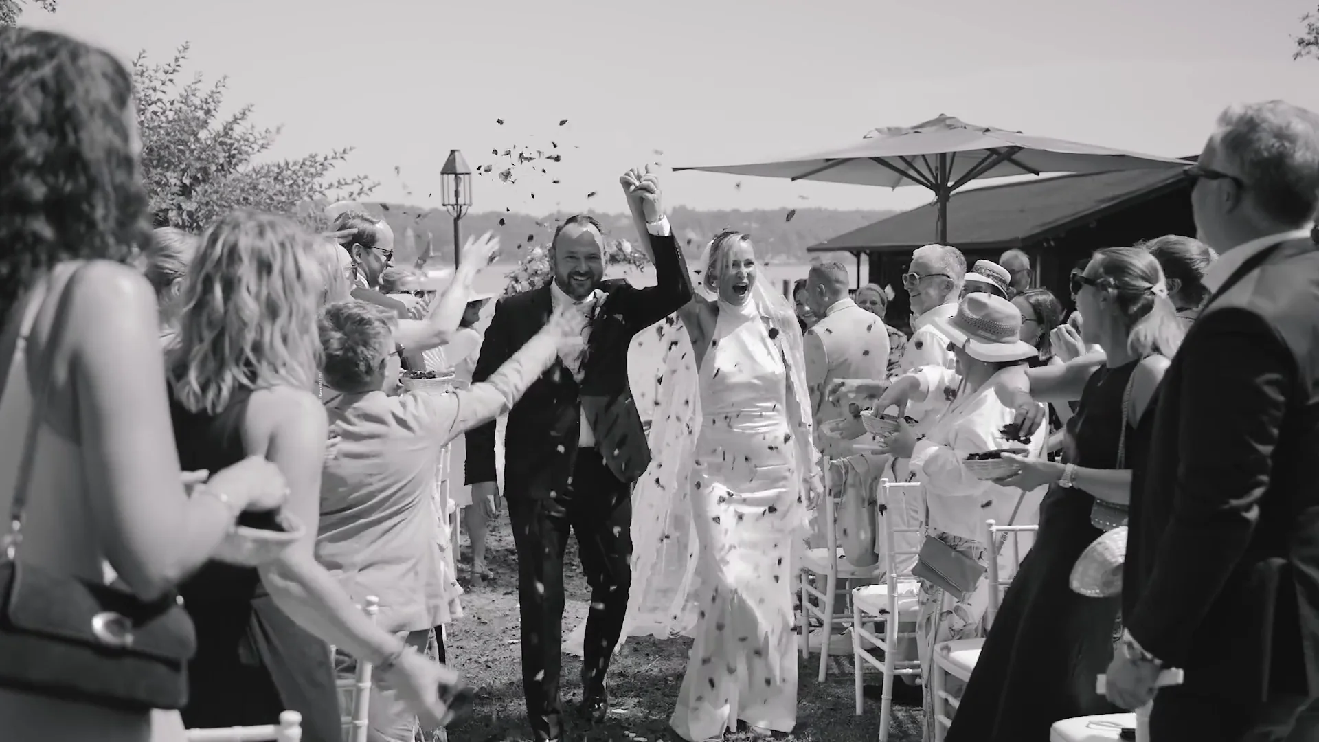 Newlyweds leaving the ceremony under confetti, black and white